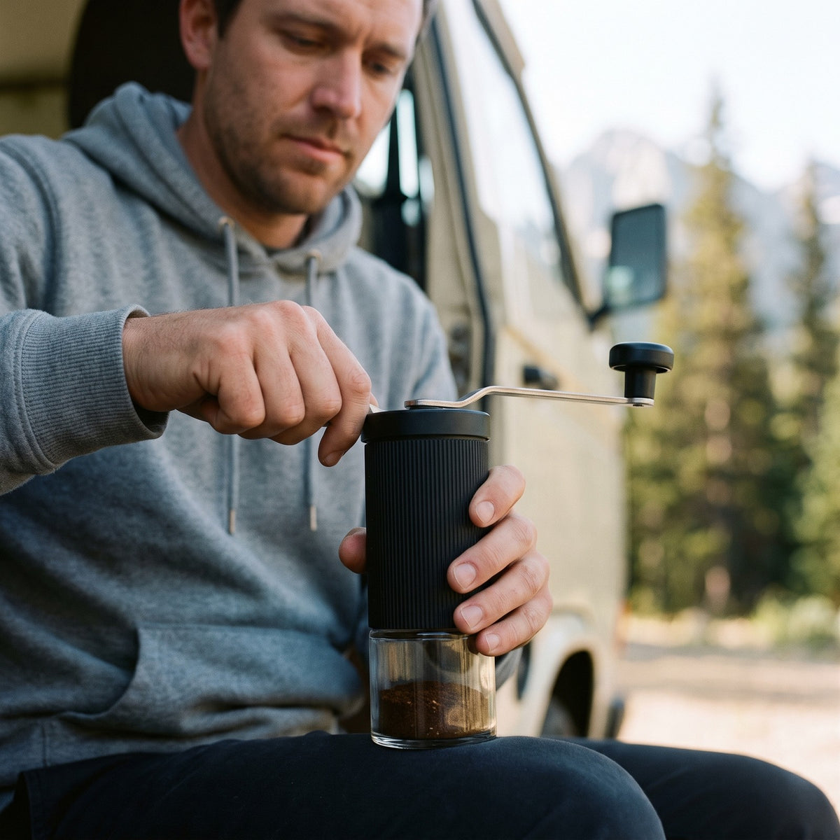 Man grinding coffee with the manual coffee grinder at a camper van