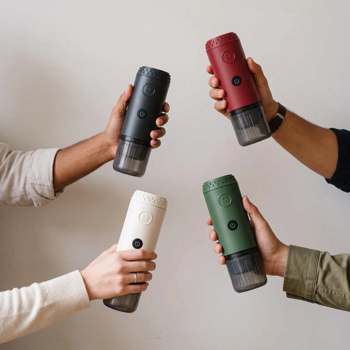 Four hands holding Origin in forest green, midnight black, cream and canyon red