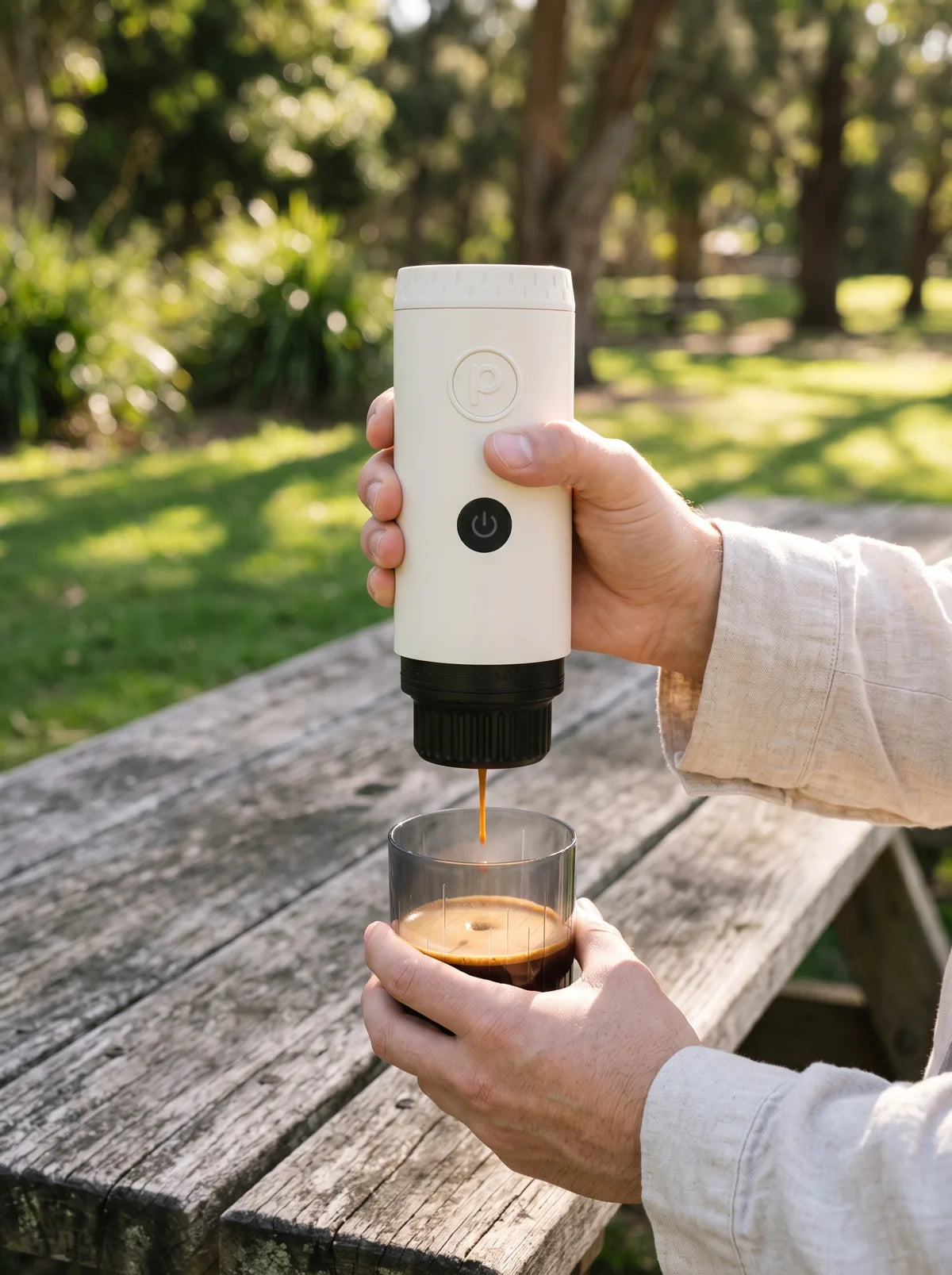 Cream Origin pouring espresso into a glass on a wooden picnic table